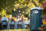 Outdoor restroom rentals near an event with people seated at tables.