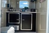 Modern restroom with a sink, toilet, and cabinet in a portable trailer.