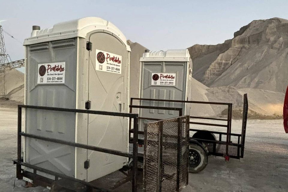 Portable toilets on a trailer in an industrial outdoor setting.